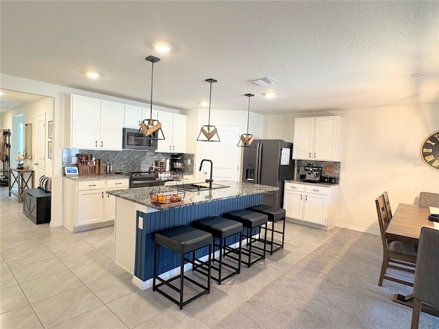 kitchen with sink, white cabinetry, appliances with stainless steel finishes, and an island with sink