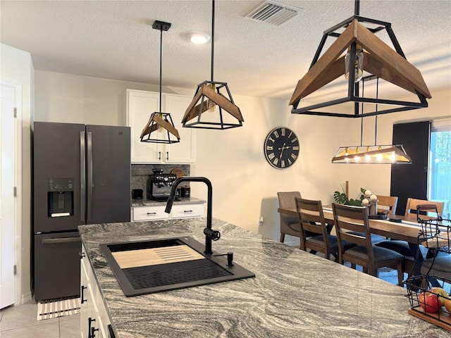 kitchen featuring stainless steel fridge with ice dispenser, white cabinetry, tasteful backsplash, and sink