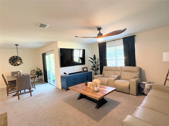 carpeted living room featuring a textured ceiling and ceiling fan