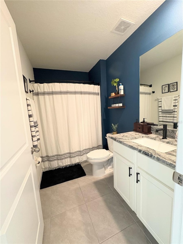 bathroom with toilet, vanity, and tile patterned flooring