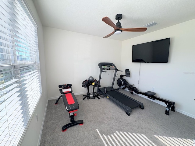 workout area with light carpet, ceiling fan, and a textured ceiling