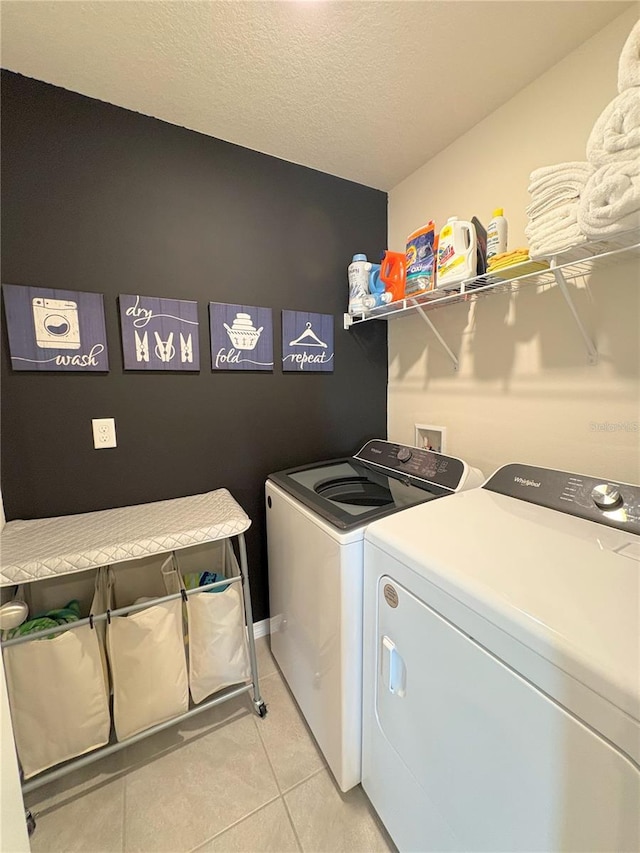 washroom with a textured ceiling, light tile patterned flooring, and washing machine and clothes dryer