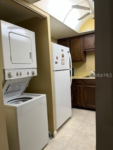 washroom featuring ceiling fan, stacked washing maching and dryer, and sink