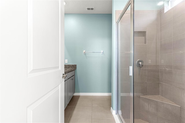 bathroom with tile patterned flooring, vanity, and a shower with door