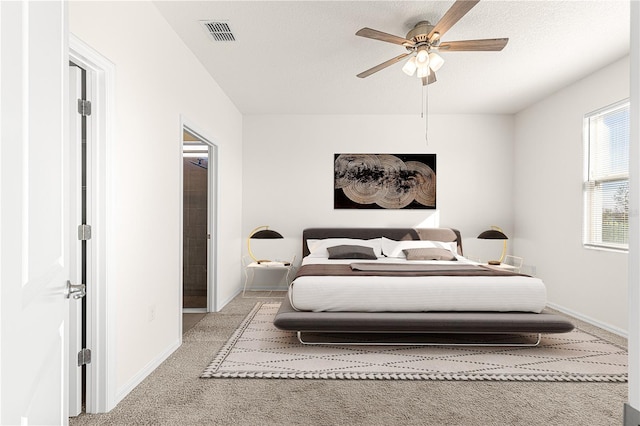 bedroom with a textured ceiling, light colored carpet, and ceiling fan