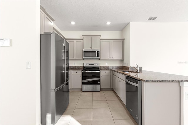 kitchen featuring gray cabinetry, sink, kitchen peninsula, light tile patterned floors, and appliances with stainless steel finishes