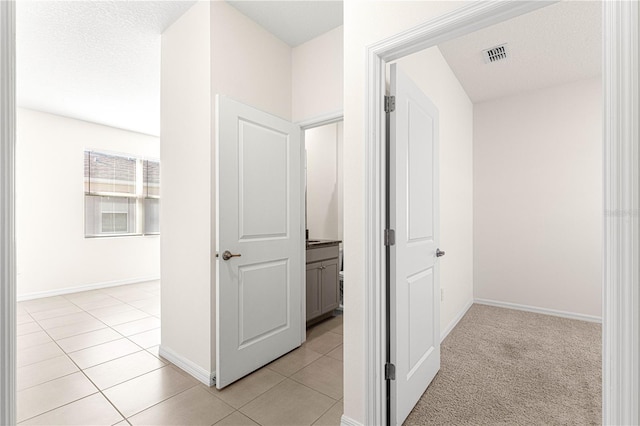 corridor featuring light tile patterned flooring and a textured ceiling