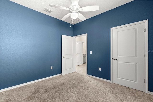 unfurnished bedroom with ceiling fan, light carpet, and a textured ceiling