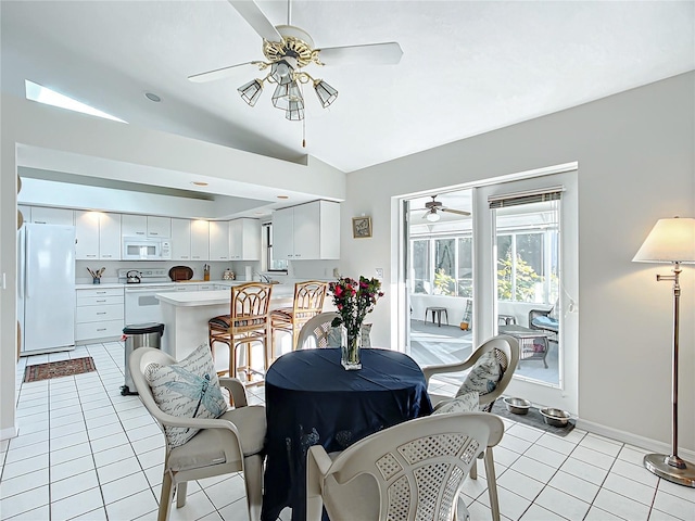 tiled dining room featuring sink and vaulted ceiling