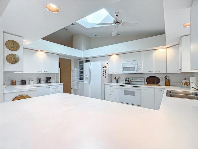 kitchen featuring white cabinets, white appliances, sink, and a skylight