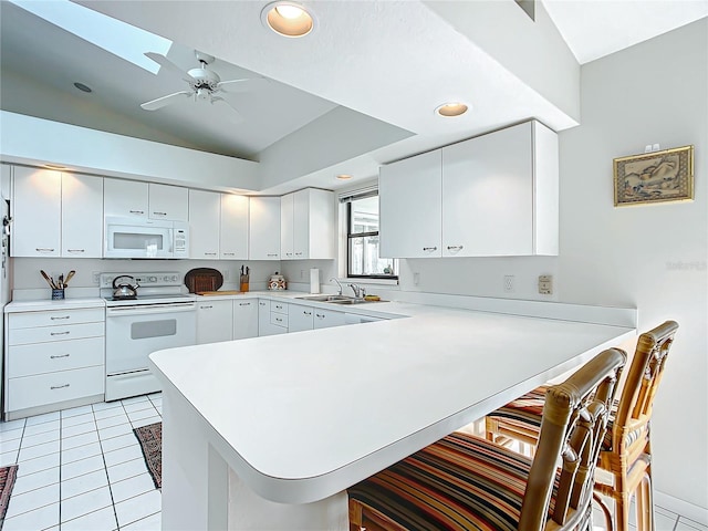 kitchen with a breakfast bar, white appliances, lofted ceiling, white cabinets, and kitchen peninsula