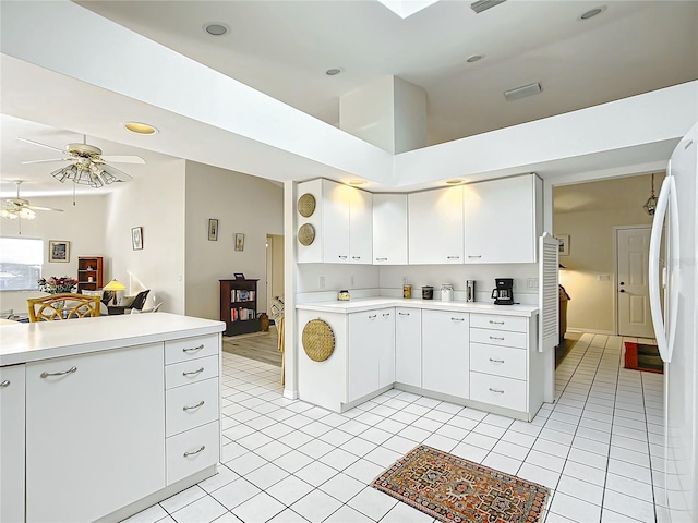 kitchen with a high ceiling, white cabinets, white refrigerator, ceiling fan, and light tile patterned floors