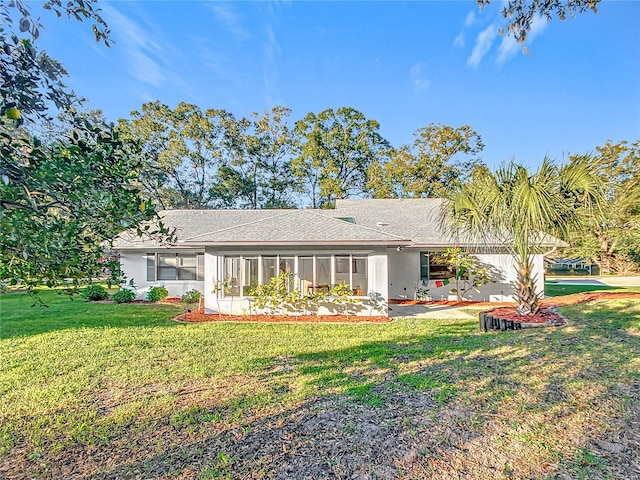 rear view of house featuring a sunroom and a yard