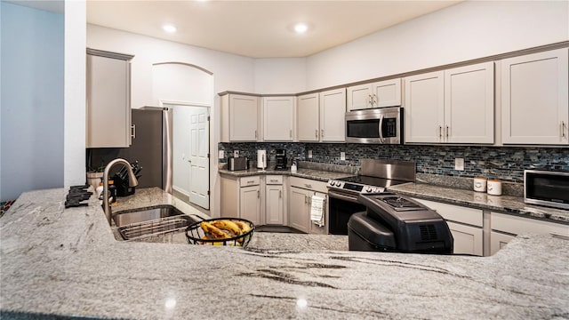 kitchen with stainless steel appliances, dark stone countertops, decorative backsplash, and sink