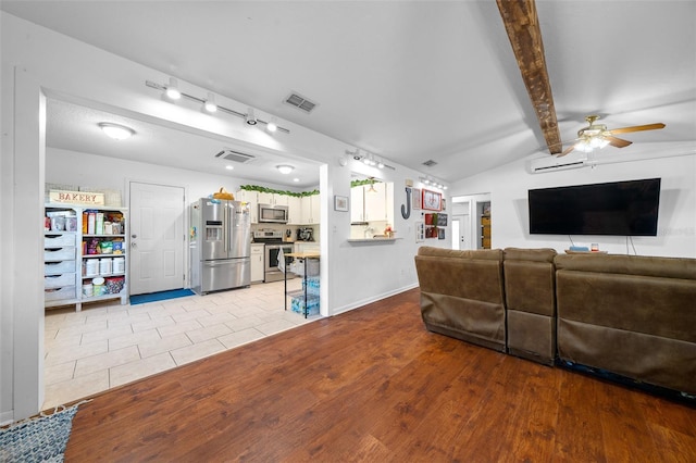 living room with a wall mounted AC, ceiling fan, vaulted ceiling with beams, and light wood-type flooring