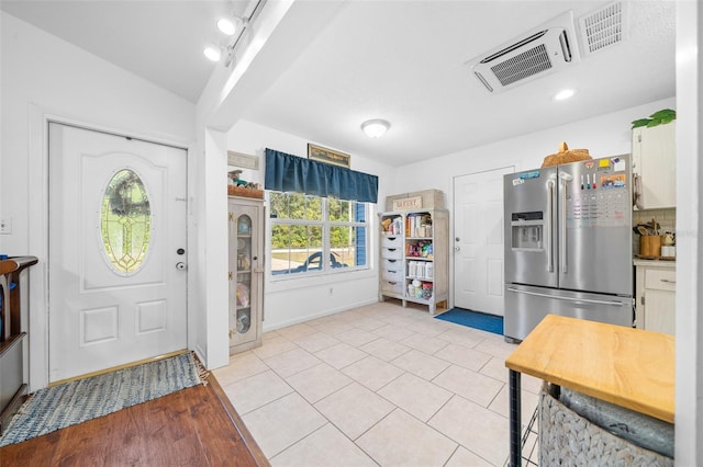 interior space with white cabinets, stainless steel fridge, and light tile patterned floors