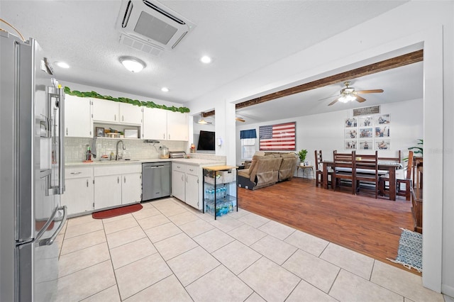 kitchen with tasteful backsplash, stainless steel appliances, ceiling fan, light tile patterned floors, and white cabinets