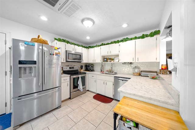 kitchen with tasteful backsplash, sink, white cabinets, and appliances with stainless steel finishes