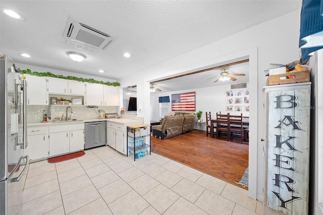 kitchen with appliances with stainless steel finishes, a textured ceiling, sink, light tile patterned floors, and white cabinets