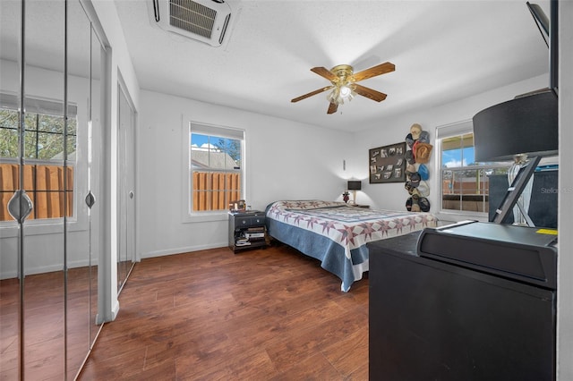 bedroom featuring multiple windows, ceiling fan, dark wood-type flooring, and a textured ceiling