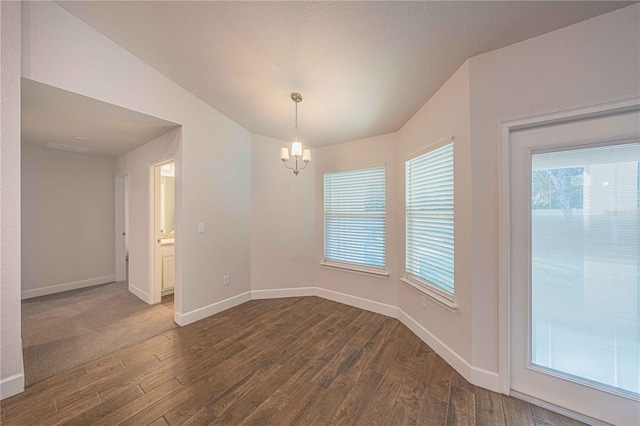 unfurnished room with vaulted ceiling, an inviting chandelier, and dark wood-type flooring