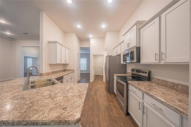 kitchen featuring light stone counters, stainless steel appliances, sink, white cabinets, and dark hardwood / wood-style floors