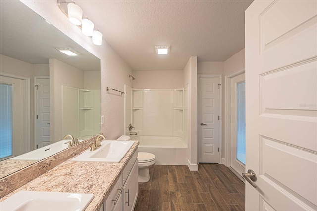 full bathroom with bathing tub / shower combination, hardwood / wood-style floors, a textured ceiling, toilet, and vanity