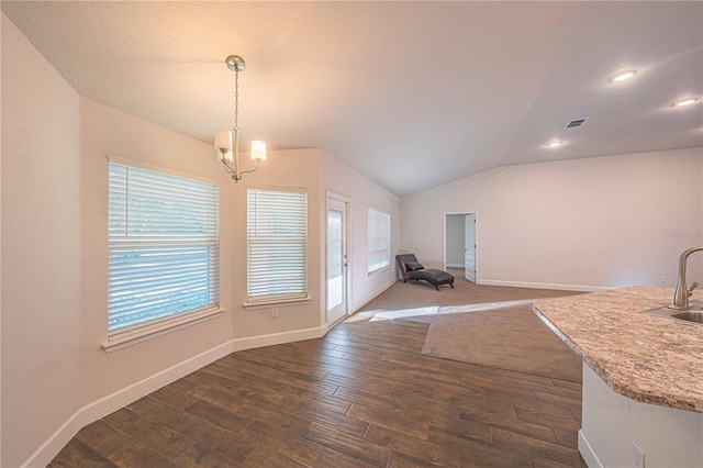 unfurnished dining area with dark hardwood / wood-style flooring, lofted ceiling, sink, and an inviting chandelier