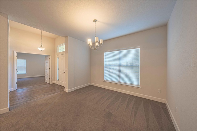 spare room with a chandelier and dark carpet