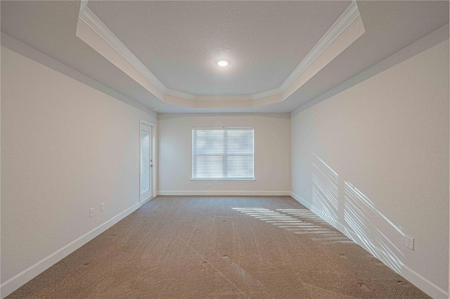 unfurnished room with a textured ceiling, a raised ceiling, ornamental molding, and carpet floors