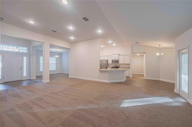 unfurnished living room featuring light colored carpet, lofted ceiling, and a notable chandelier