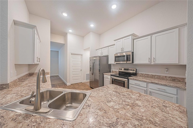 kitchen featuring white cabinets, sink, stainless steel appliances, and light hardwood / wood-style flooring