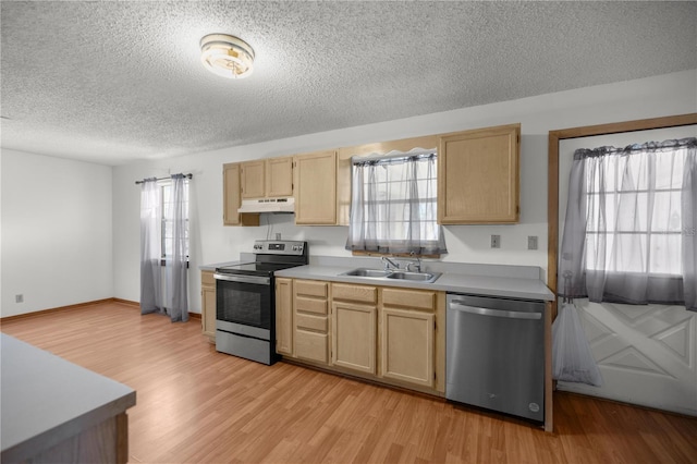 kitchen with sink, light brown cabinets, light hardwood / wood-style floors, a textured ceiling, and appliances with stainless steel finishes