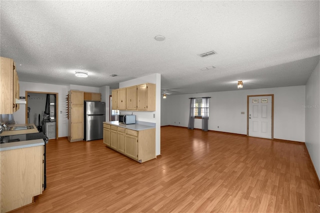 kitchen with a textured ceiling, light hardwood / wood-style floors, light brown cabinets, and stainless steel refrigerator