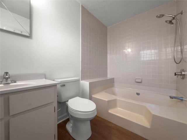 full bathroom with wood-type flooring, a textured ceiling, toilet, vanity, and tiled shower / bath