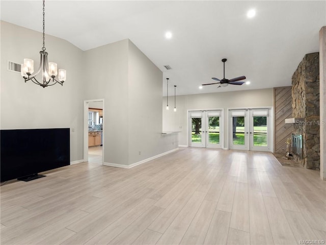 unfurnished living room featuring french doors, ceiling fan with notable chandelier, light hardwood / wood-style floors, and lofted ceiling