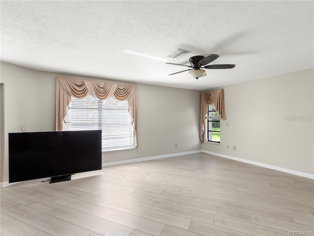 empty room with ceiling fan, light hardwood / wood-style flooring, and a textured ceiling