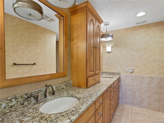 bathroom with a textured ceiling, vanity, tile patterned floors, and tile walls