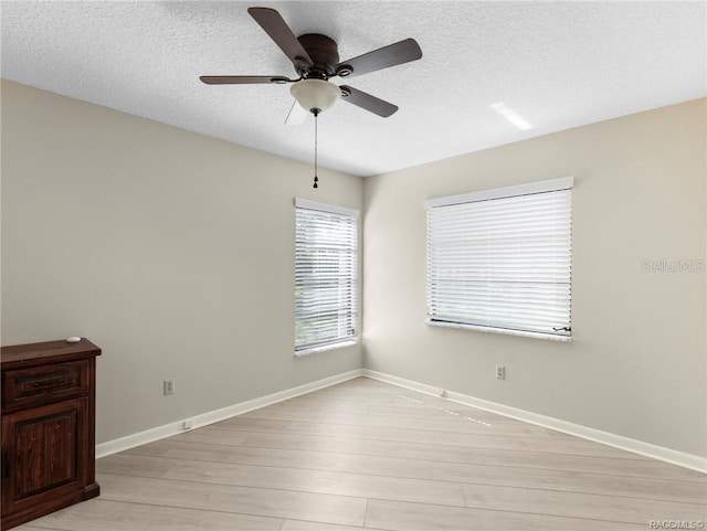 unfurnished room featuring ceiling fan, a textured ceiling, and light hardwood / wood-style flooring