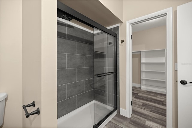 bathroom with toilet, an enclosed shower, and hardwood / wood-style flooring