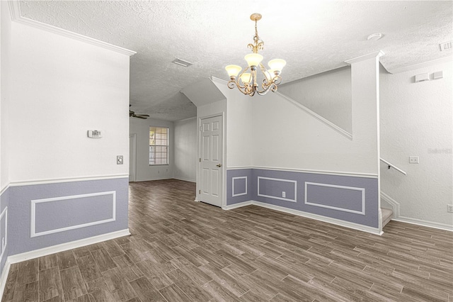 unfurnished dining area with dark wood-type flooring, a chandelier, a textured ceiling, and ornamental molding