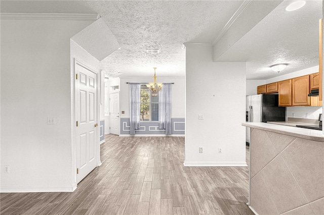 kitchen with pendant lighting, light wood-type flooring, an inviting chandelier, and ornamental molding