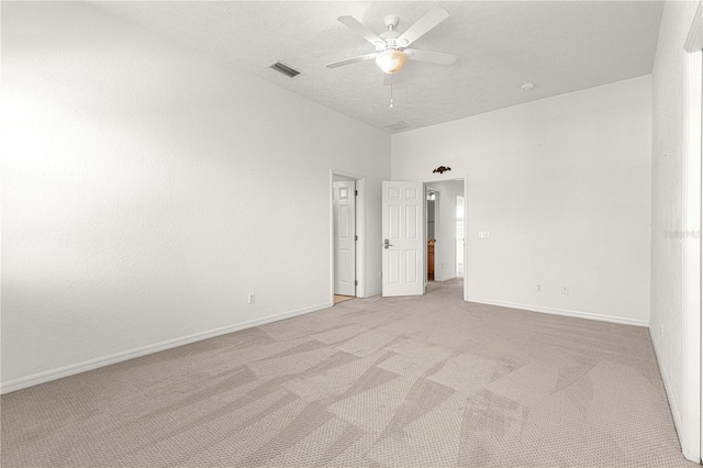 spare room featuring a textured ceiling, light carpet, ceiling fan, and a high ceiling