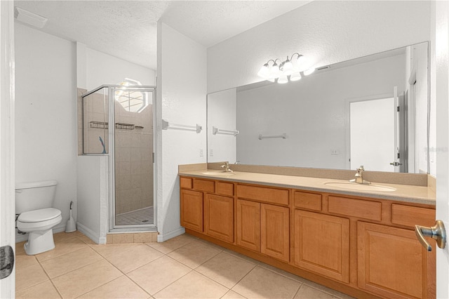 bathroom featuring vanity, tile patterned flooring, toilet, a textured ceiling, and a shower with shower door