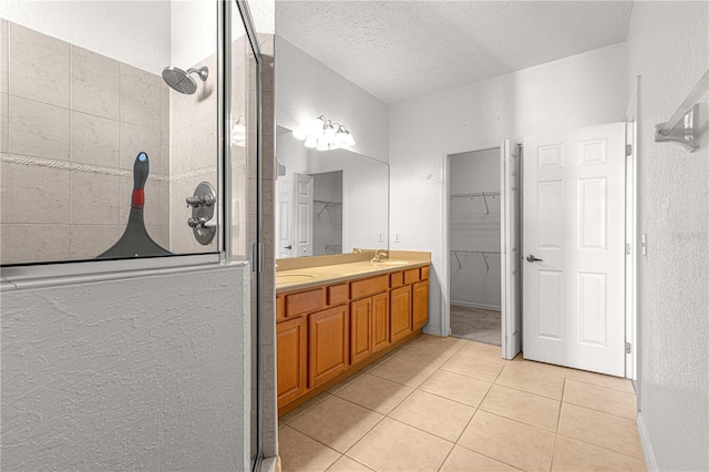 bathroom with vanity, a textured ceiling, tile patterned floors, and a shower with shower door