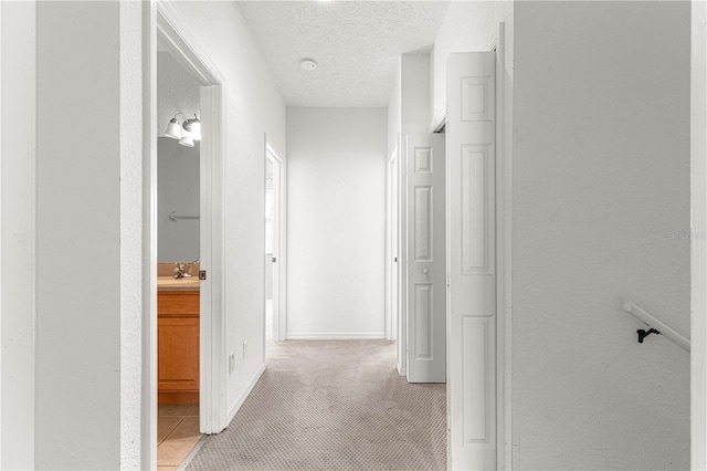 hall featuring a textured ceiling and light carpet