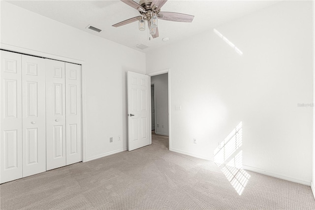 unfurnished bedroom with ceiling fan, a closet, and light carpet