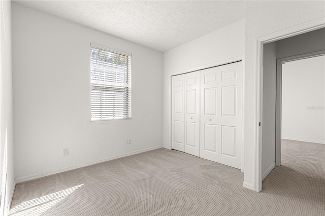 unfurnished bedroom featuring a closet, light colored carpet, and a textured ceiling