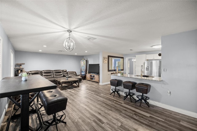 living room featuring hardwood / wood-style floors, an inviting chandelier, sink, and a textured ceiling