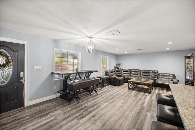 living room with hardwood / wood-style flooring, a textured ceiling, and an inviting chandelier